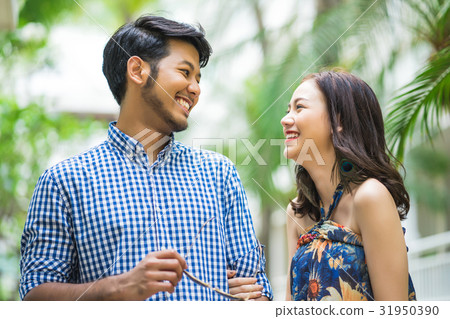 A photo of a young couple looking each other and smiling happily. 31950390