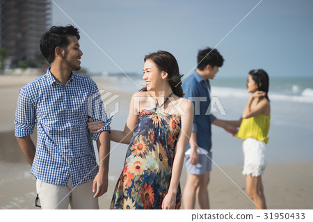 A photo of two couples arm in arm and being happy on the beach. A photo of two couples arm in arm and being happy on the beach. 31950433