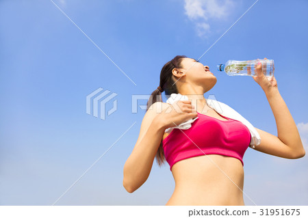 sporty woman drinking water bottle after jogging sporty woman drinking water bottle after jogging 31951675