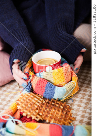 Cup of hot tea wrapped in knitted scarf holding by Cup of hot tea wrapped in knitted scarf holding by 31952100