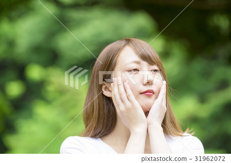 A young woman looks at his hands on his cheeks A young woman looks at his hands on his cheeks 31962072