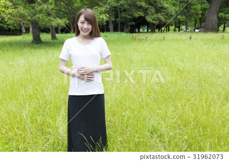 A young woman standing in a park of fresh green A young woman standing in a park of fresh green 31962073
