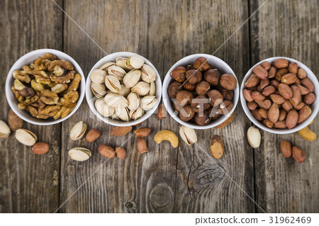 Four bowls with nuts on a  wooden table 31962469