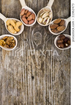 Nuts in a wooden spoons on a wooden table. Nuts in a wooden spoons on a wooden table. 31962473