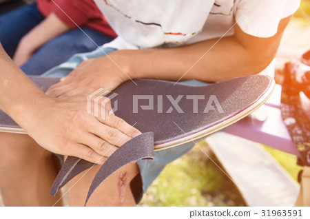 Boy cleans the trimmed edge the griptape on a Boy cleans the trimmed edge the griptape on a 31963591