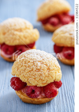 Eclairs with mascarpone cream and raspberries. 31964522