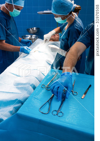 Surgeon taking a scissors from tray 31970508