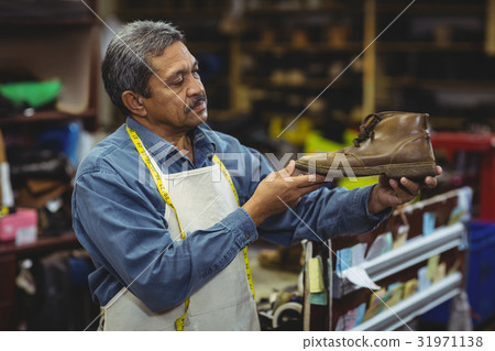 Shoemaker examining a shoe Shoemaker examining a shoe 31971138