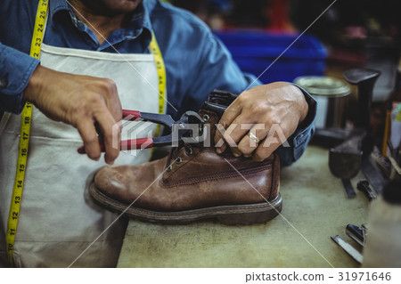 Shoemaker repairing a shoe Shoemaker repairing a shoe 31971646