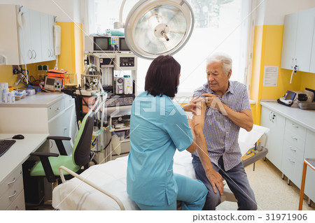 Female doctor giving an injection to a patient Female doctor giving an injection to a patient 31971906