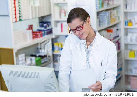 Pharmacist holding prescription paper while talking on phone 31971991