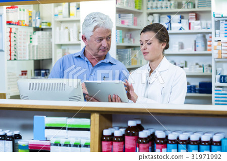 Pharmacists using digital tablet at counter 31971992