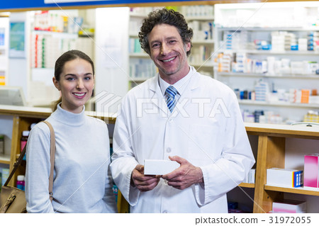 Smiling customer and pharmacist holding drug box in pharmacy Smiling customer and pharmacist holding drug box in pharmacy 31972055
