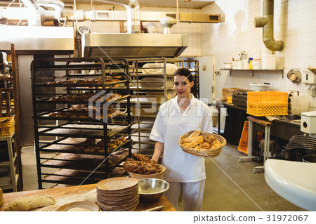 Female baker holding basket of sweet foods Female baker holding basket of sweet foods 31972067
