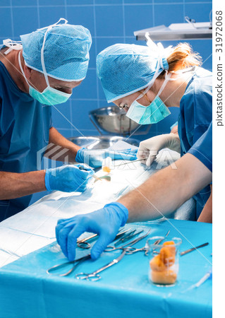 Surgery team operating a patient in an operating room Surgery team operating a patient in an operating room 31972068