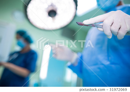 Surgeon holding surgical tool in operation room Surgeon holding surgical tool in operation room 31972069