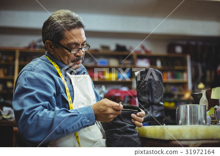 Shoemaker applying glue on shoe 31972164