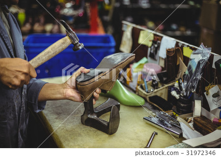 Shoemaker hammering on a shoe 31972346