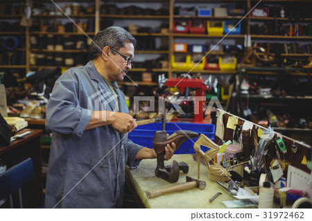 Shoemaker hammering on a shoe 31972462