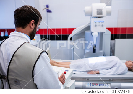Doctor using x-ray machine to examine patient 31972486