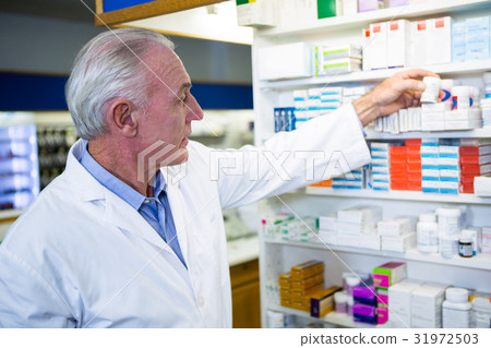 Pharmacist checking a bottle of drug 31972503