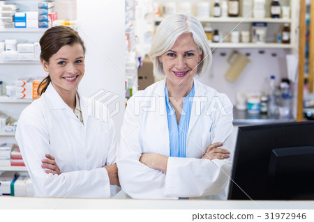 Smiling pharmacists standing with arms crossed in pharmacy 31972946