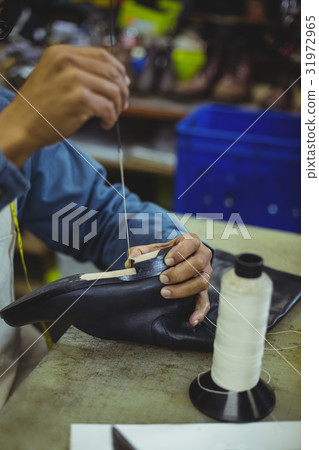 Shoemaker stitching shoe sole with needle 31972965