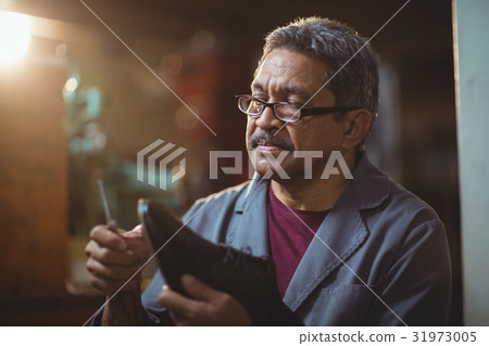 Shoemaker repairing a shoe 31973005