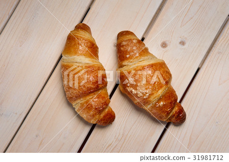 A pair of fresh croissant on the table, top view. A pair of fresh croissant on the table, top view. 31981712