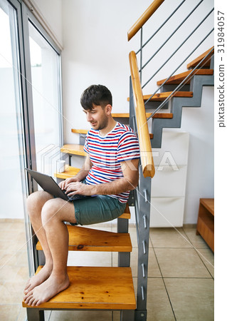 Handsome man working on laptop at home Handsome man working on laptop at home 31984057