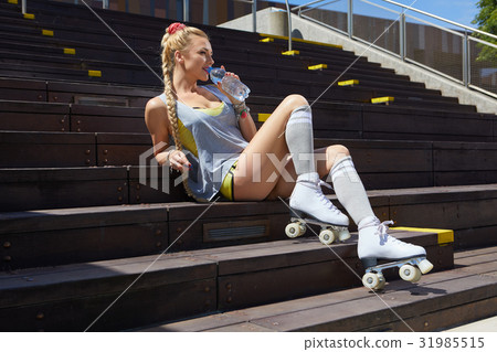 blond girl on roller skates sitting in a city park of the rive blond girl on roller skates sitting in a city park of the rive 31985515