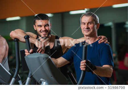 Senior man working with personal trainer in gym Senior man working with personal trainer in gym 31986700