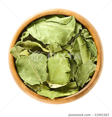 Dried kaffir lime leaves in wooden bowl over white Dried kaffir lime leaves in wooden bowl over white 31991987