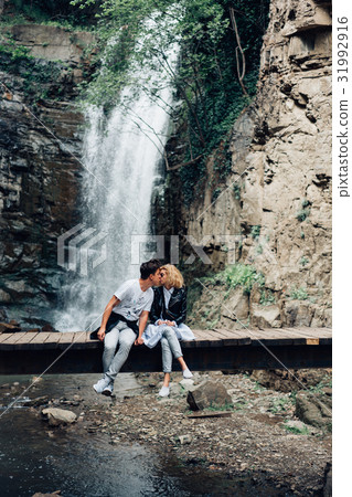 A guy and girl are sitting on a bridge A guy and girl are sitting on a bridge 31992916