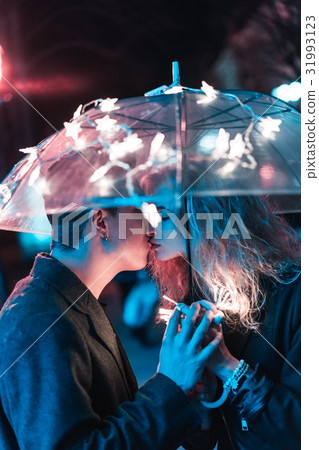 Guy and girl kissing under an umbrella Guy and girl kissing under an umbrella 31993123