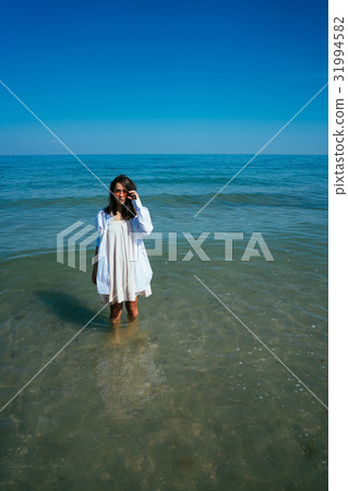 The girl is standing in the sea by the shore 31994582