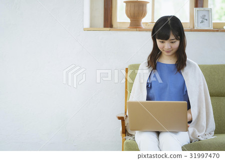 A woman using a laptop computer on a sofa A woman using a laptop computer on a sofa 31997470
