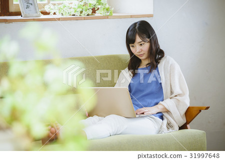 A woman using a laptop computer on a sofa A woman using a laptop computer on a sofa 31997648