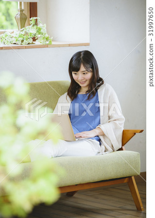 A woman using a laptop computer on a sofa A woman using a laptop computer on a sofa 31997650