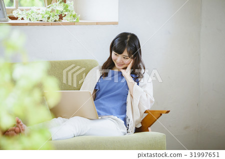 使用便攜式計算機的婦女在沙發 使用便攜式計算機的婦女在沙發 31997651