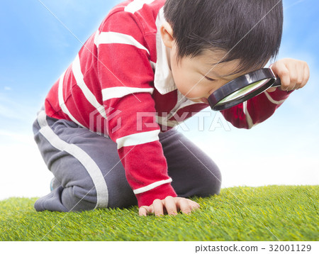 a boy exploring nature with magnifying glass 32001129