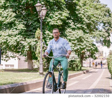 Businessman riding bicycle to work on urban street 32002150