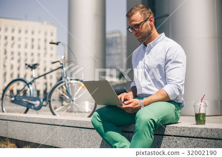 Busy happy man working on laptop outside corporate 32002190