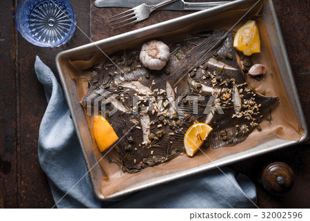 圖庫照片: baking tray with flounder and seasoning on the