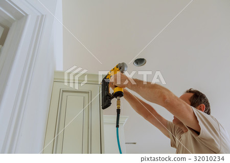 Carpenter brad using nail gun to Crown Moulding Carpenter brad using nail gun to Crown Moulding 32010234