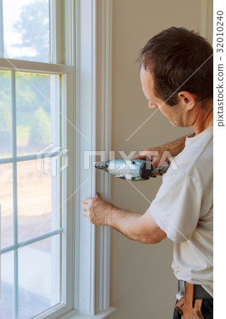 Carpenter brad using nail gun to moldings windows 32010240