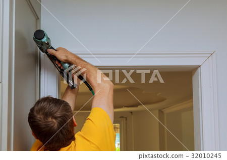 Carpenter brad using nail gun to moldings  32010245