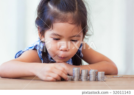 girl playing with coins making stacks of money 32011143
