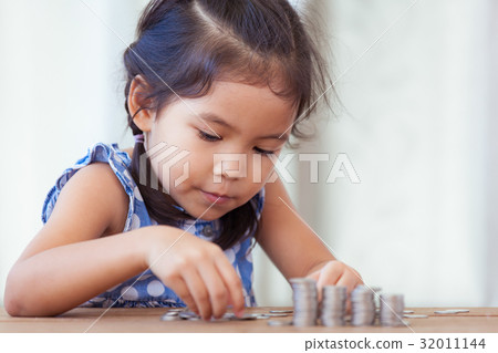girl playing with coins making stacks of money girl playing with coins making stacks of money 32011144