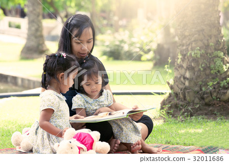 Mother and little daughter reading book together Mother and little daughter reading book together 32011686